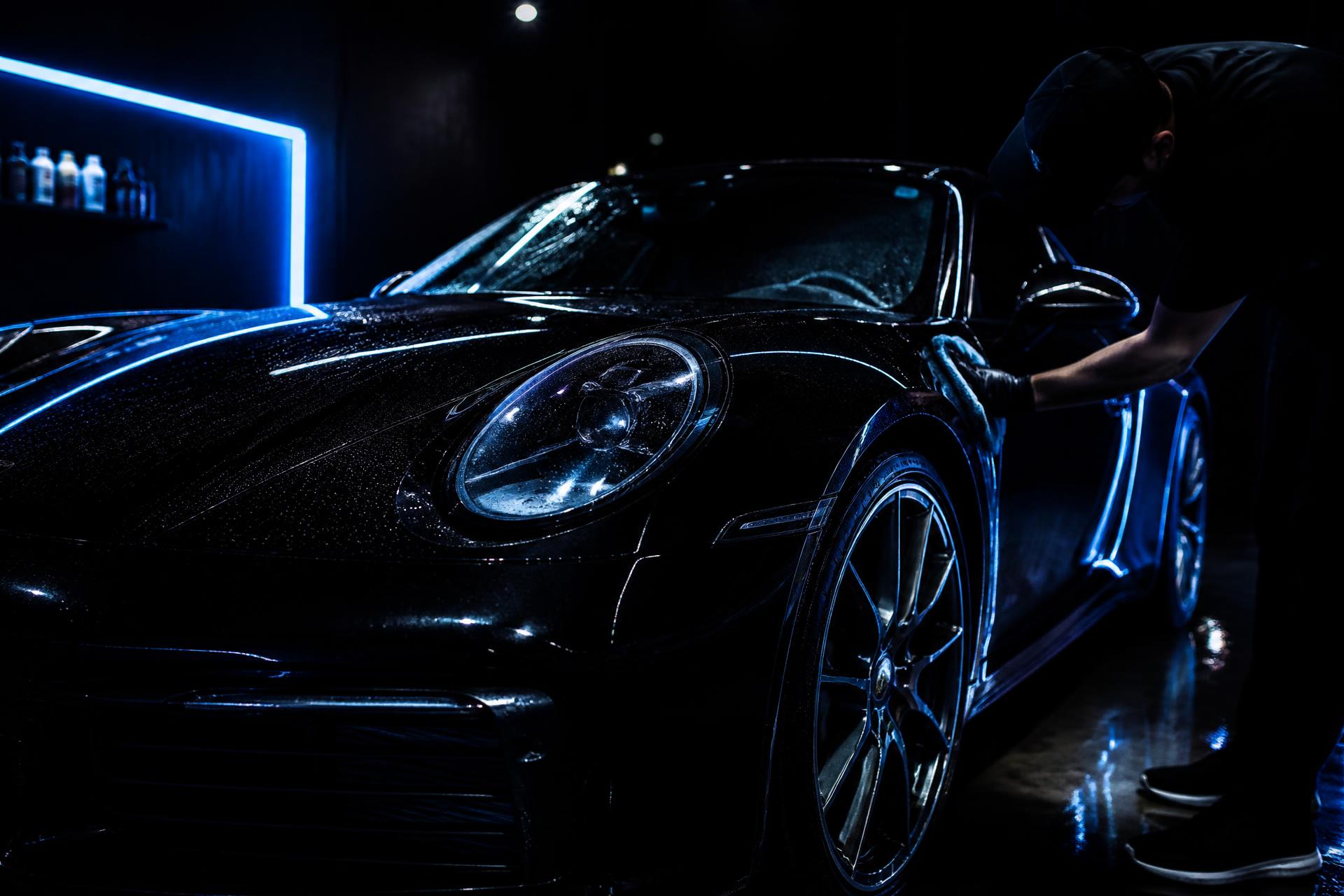 Detailer polishing a glossy black car